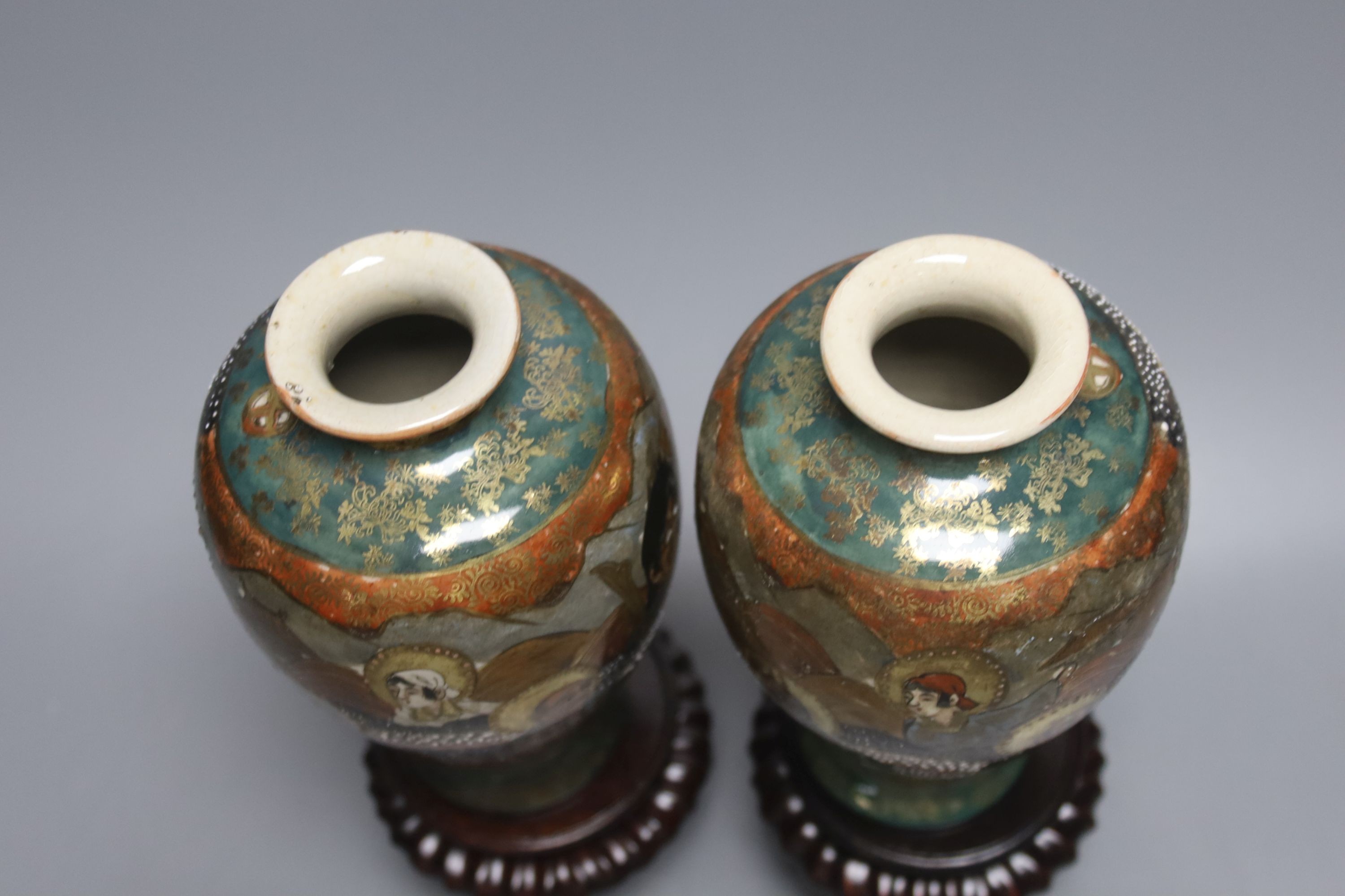 A pair of Japanese Satsuma pottery vases, depicting immortals, 17.5cm, wood stands